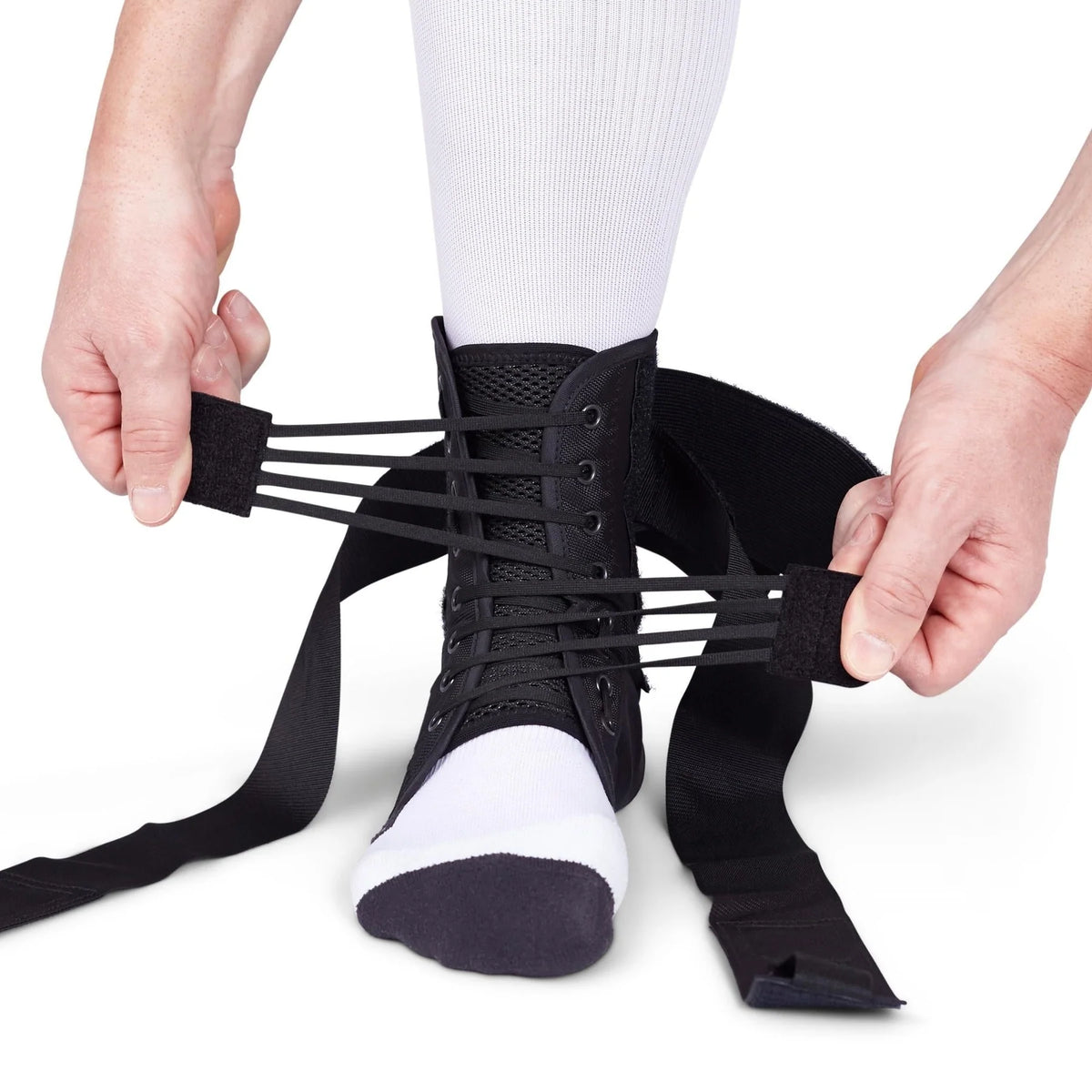 Ankle brace with lace-up front and wrap straps being secured over a white sock on a foot