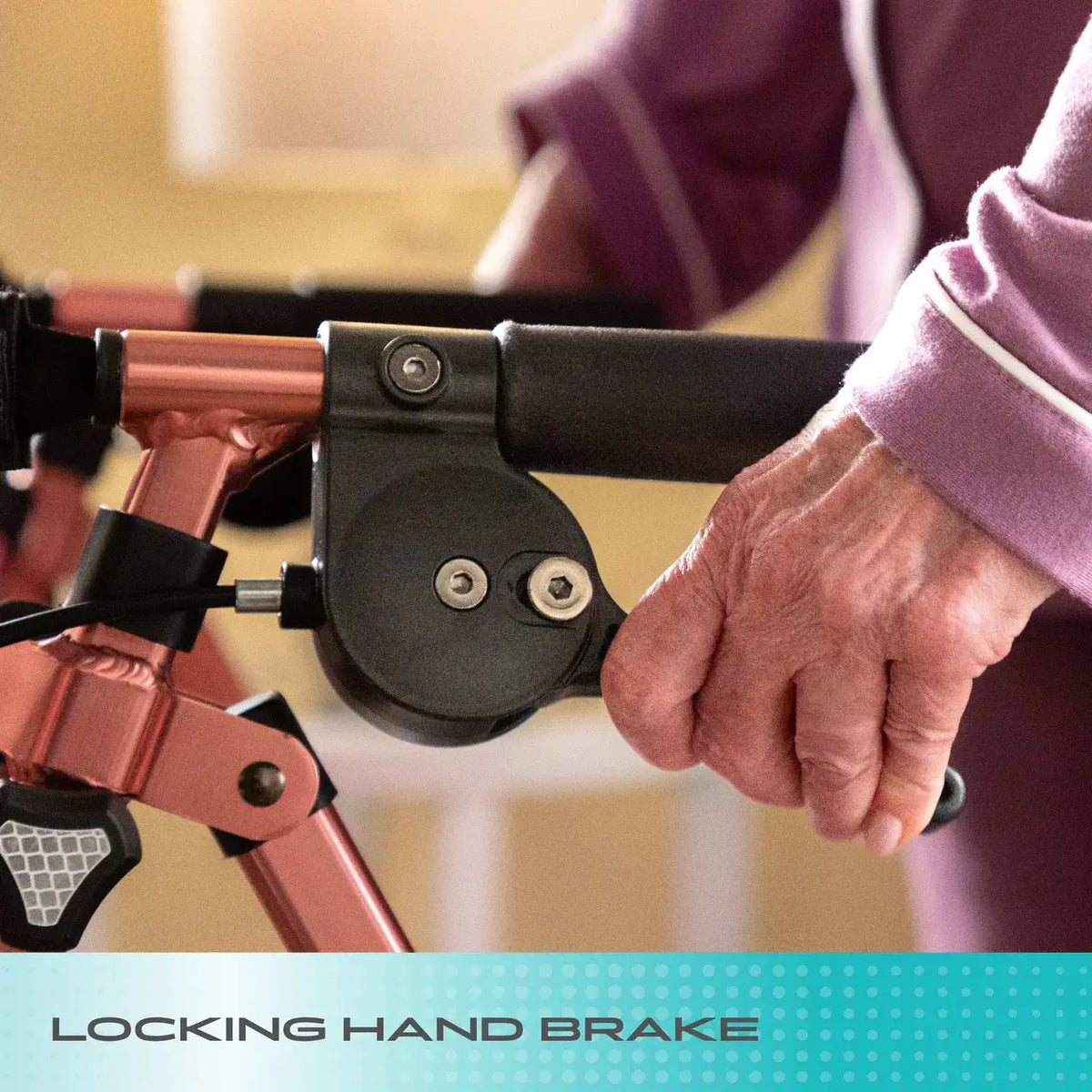 Rollator locking hand brake handle gripped by an elderly person's hand, shown close up on a rose-colored folding frame