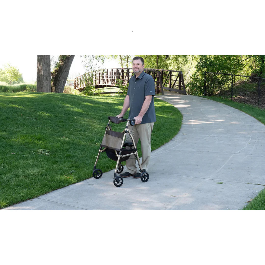Rollator walker with padded seat and storage bag, used by a man walking on an outdoor park pathway