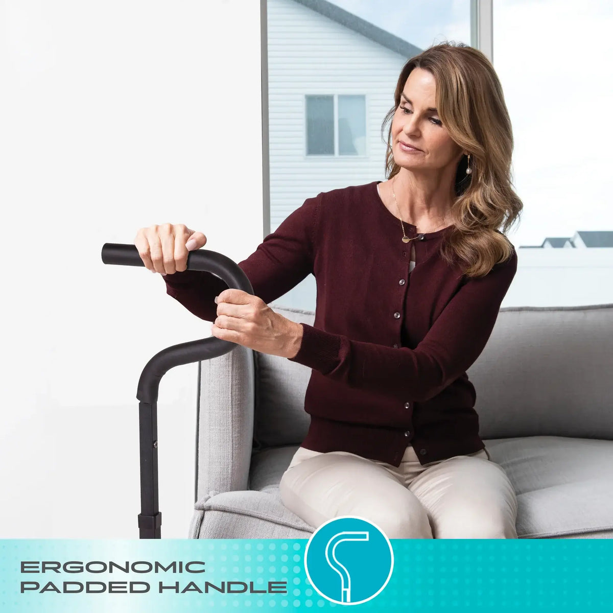 Chair cane with ergonomic padded handle used by a woman seated on a sofa to assist with standing up
