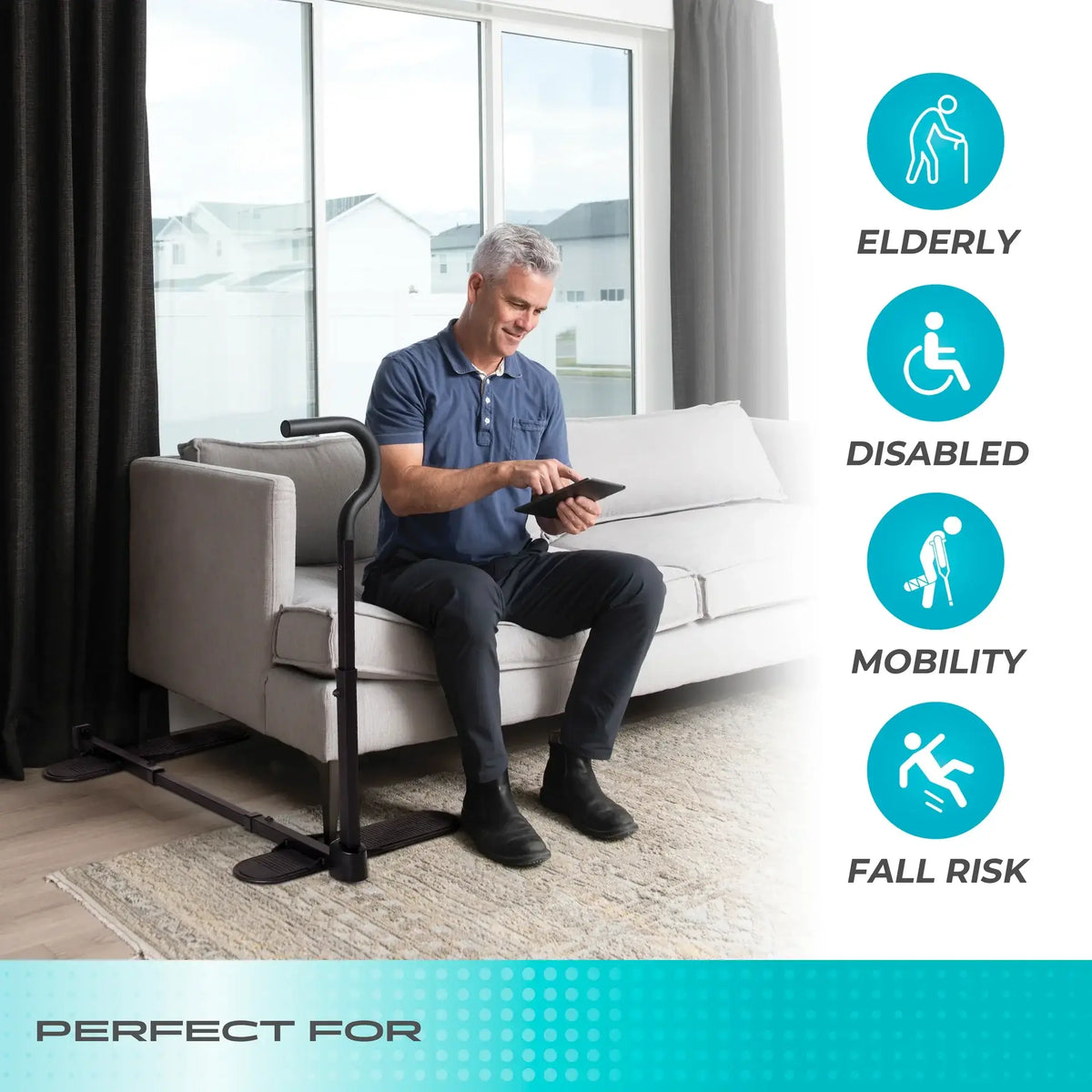 Stander Chair Cane compact standing assist handle beside a sofa with a man seated nearby holding a tablet