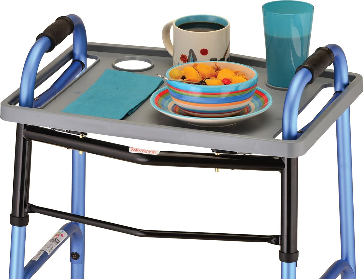 Universal walker tray in gray with cup holders attached to a blue folding walker, holding a bowl, mug, cup, and napkin