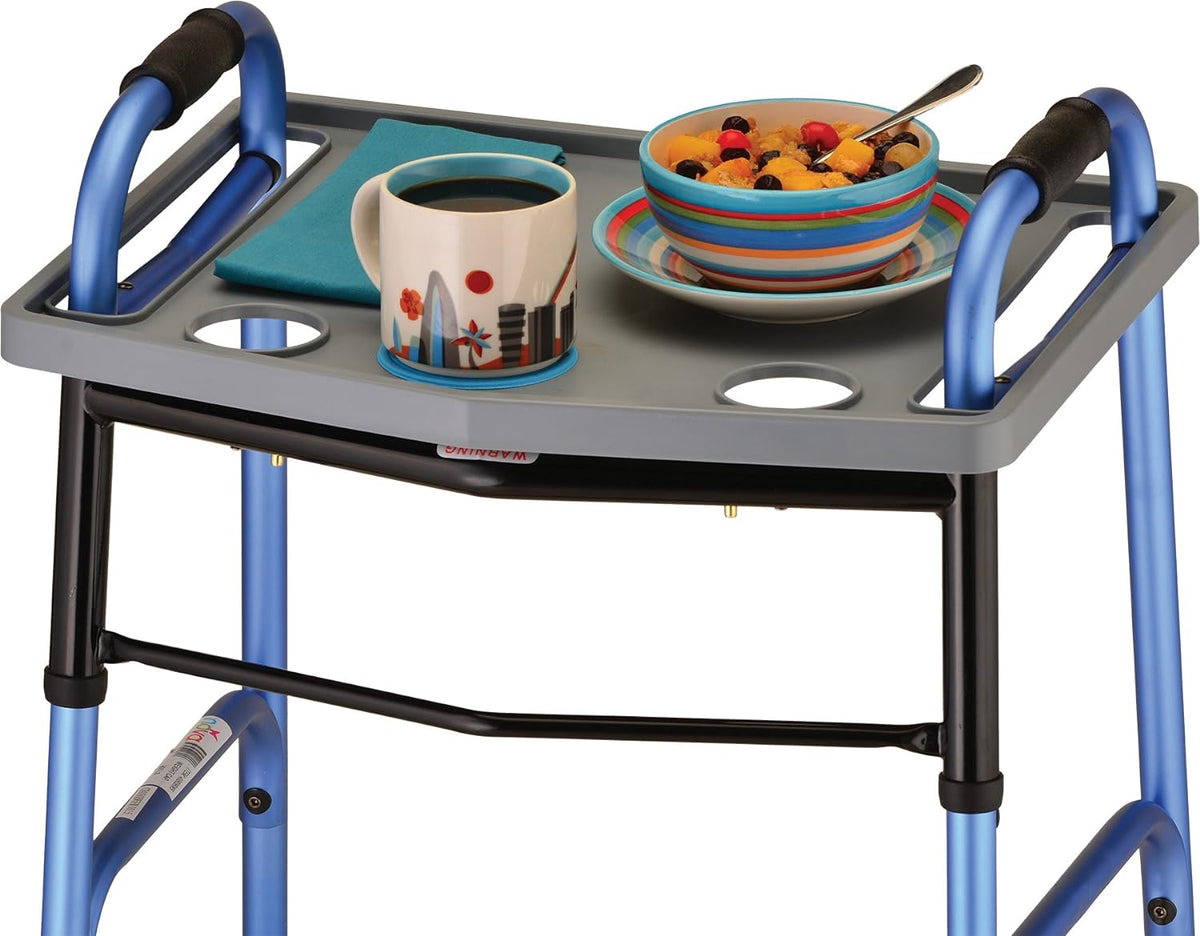 Walker tray in gray attached to a blue folding walker, holding a coffee mug, bowl of fruit, plate, and napkin