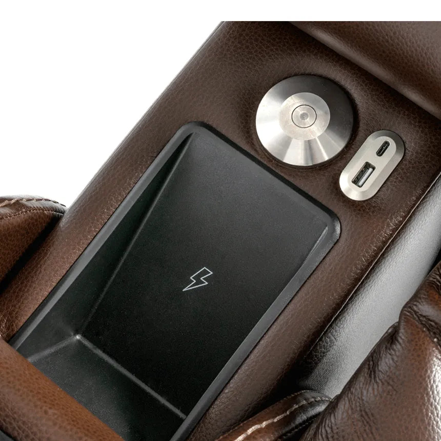 Lift chair armrest detail showing wireless charging pad, USB-A and USB-C ports, and a round control button on brown leather