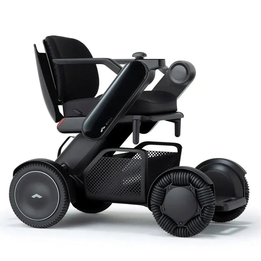 Power wheelchair in matte black with mesh seat back, joystick controller, under-seat storage basket, and four large textured