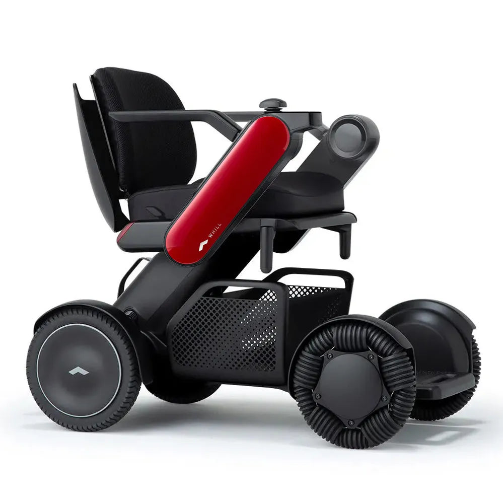 Power wheelchair with black mesh seat, red side panel, joystick controller, under-seat basket, and wide omnidirectional