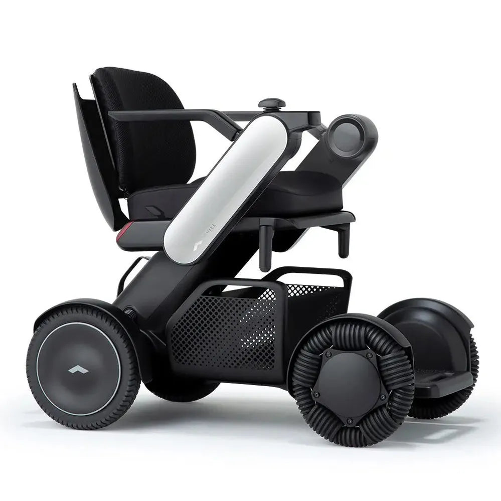 Power wheelchair with sleek black frame, mesh back seat, white battery pack, joystick controller, and four ribbed wheels on