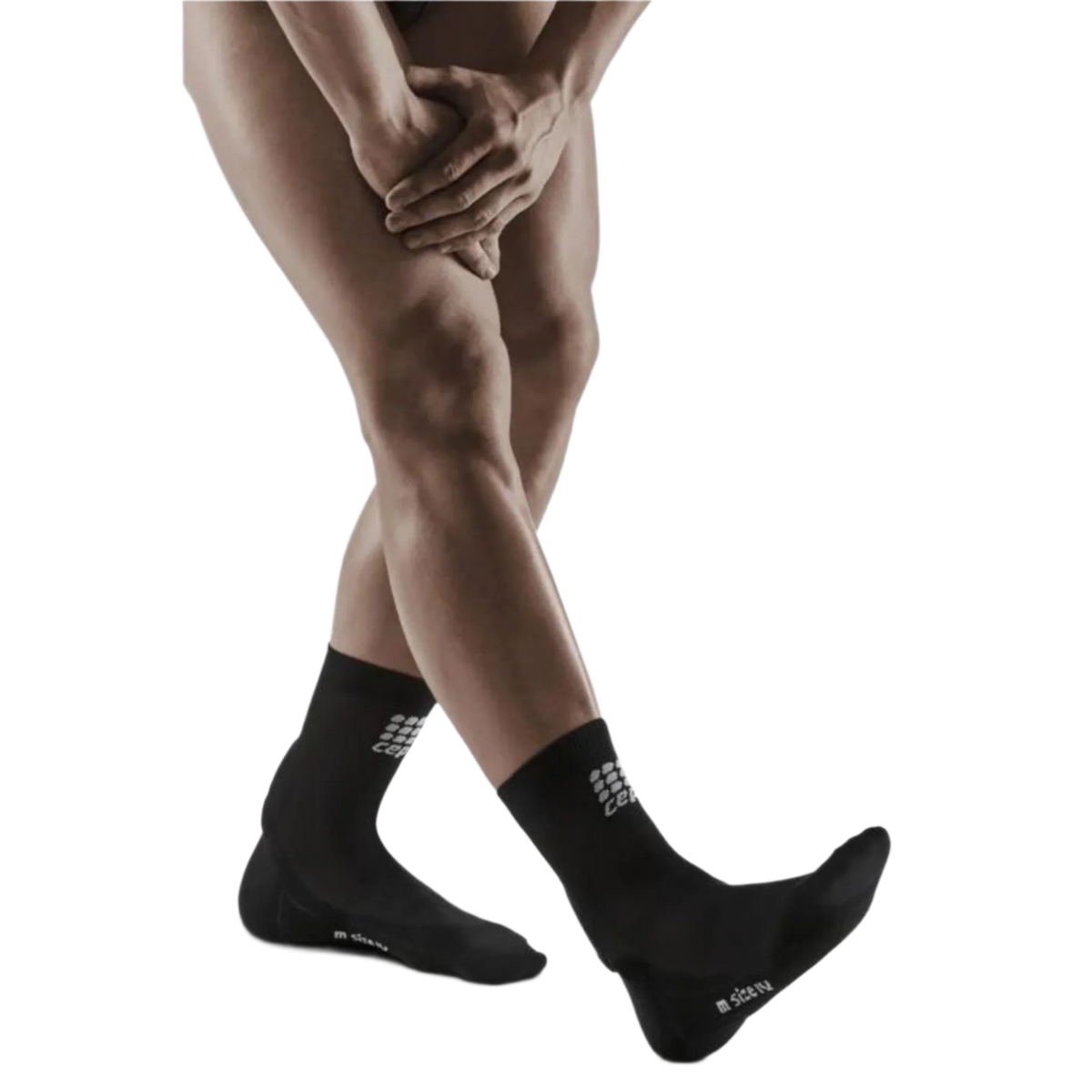 Achilles support short compression socks in black worn on a man's feet and lower legs, shown from the shins down