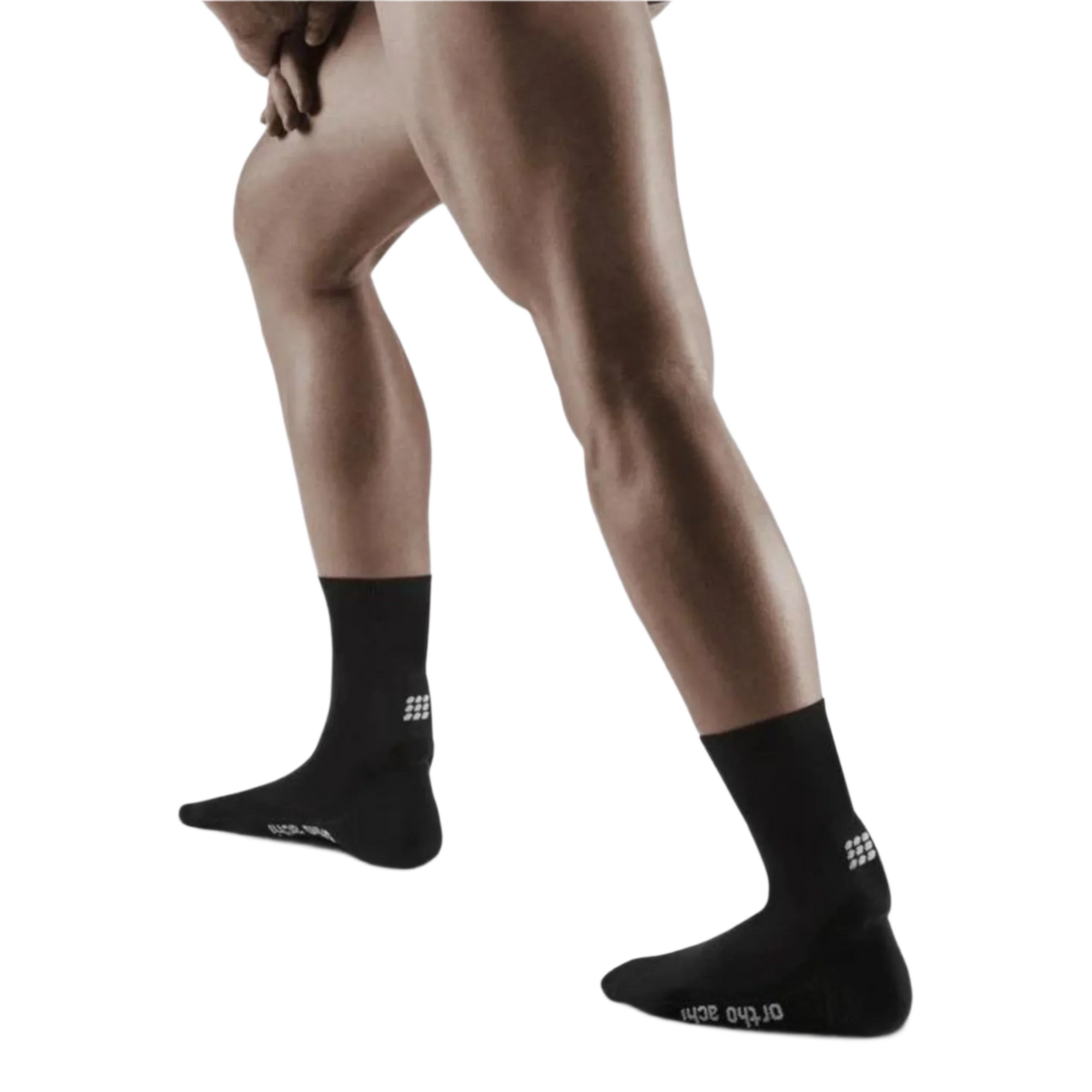 Achilles support short socks in black worn on both feet, shown from the side on a standing male model