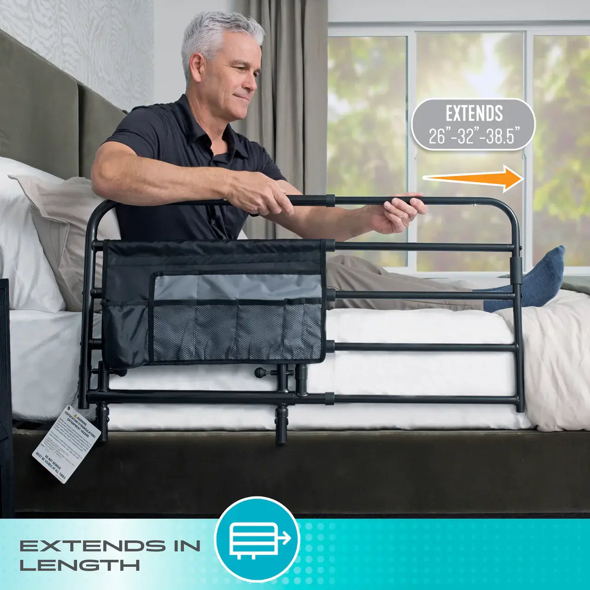 Bed rail with storage pouch shown extended in length, with older adult gripping the black metal adjustable rail from bed