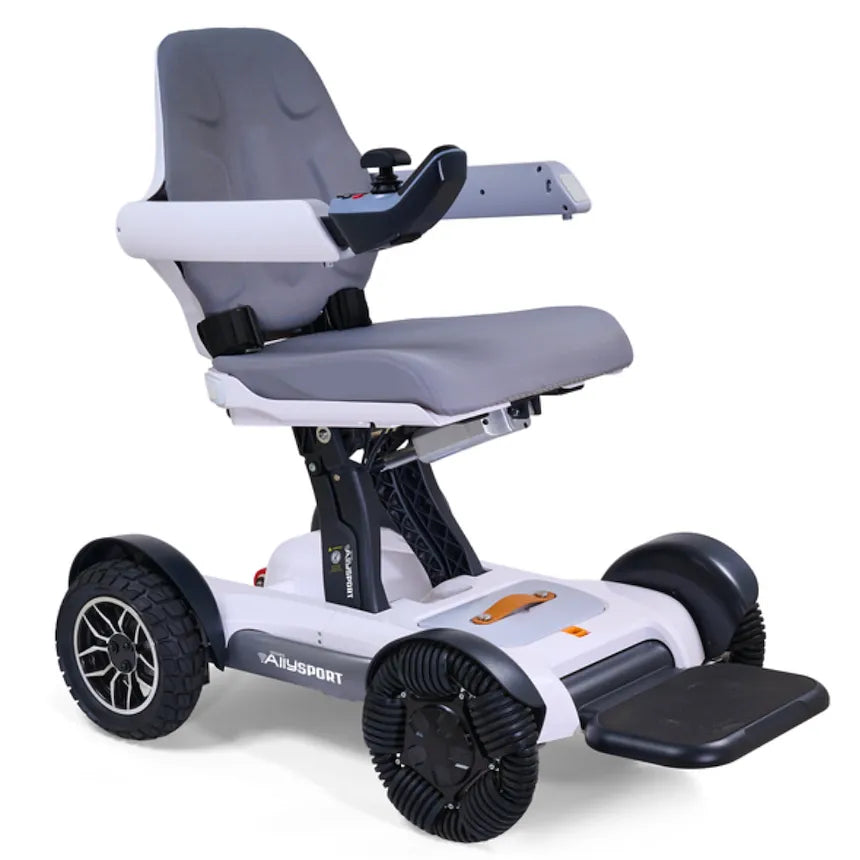 Power wheelchair with gray padded seat, white frame, joystick armrest control, footrest, and four all-terrain wheels