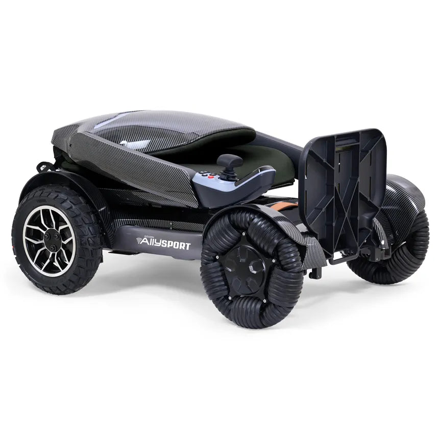 Power wheelchair with carbon fiber styling, joystick control, large all-terrain front wheels, and folding footrest, shown on