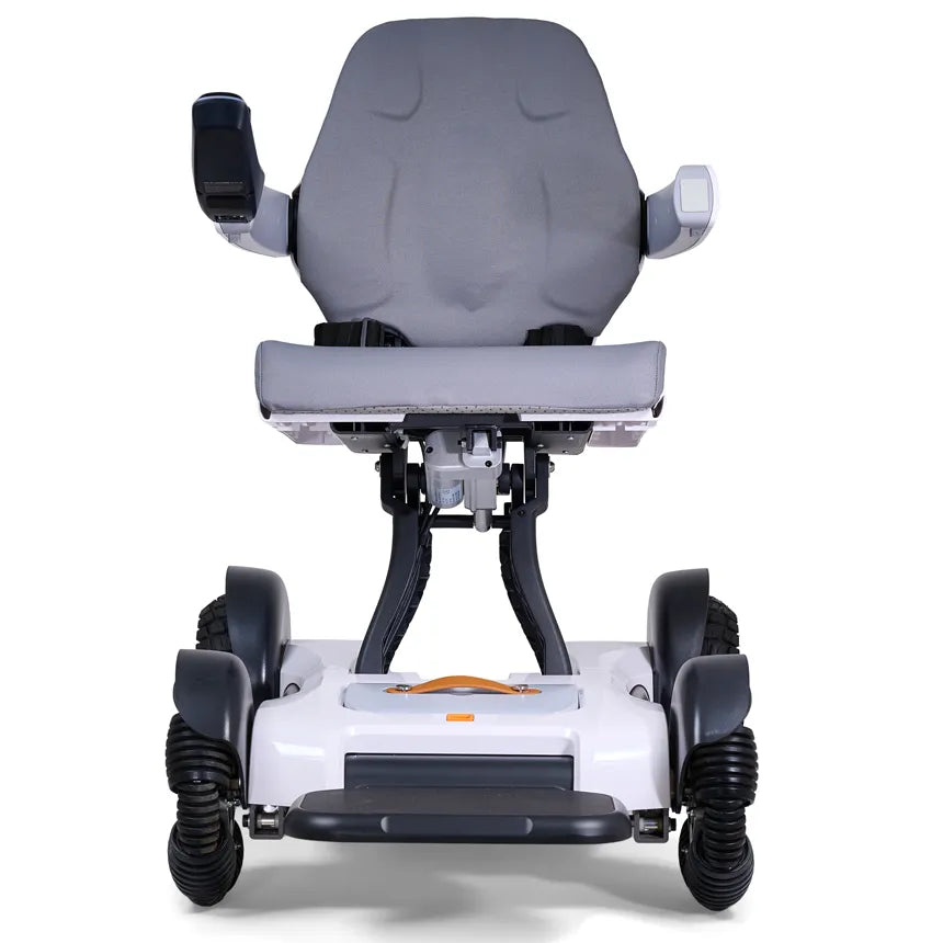 Power wheelchair with gray padded seat and back, joystick armrest, white base, orange accent handle, and four rugged wheels