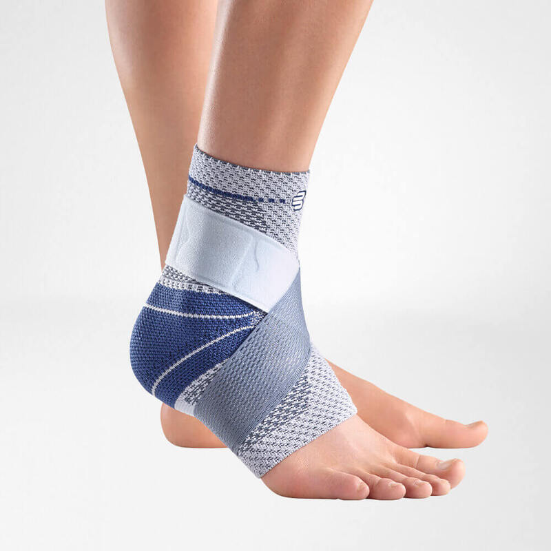 Ankle brace with gray knit fabric and blue diagonal straps worn on a bare foot and ankle, side view