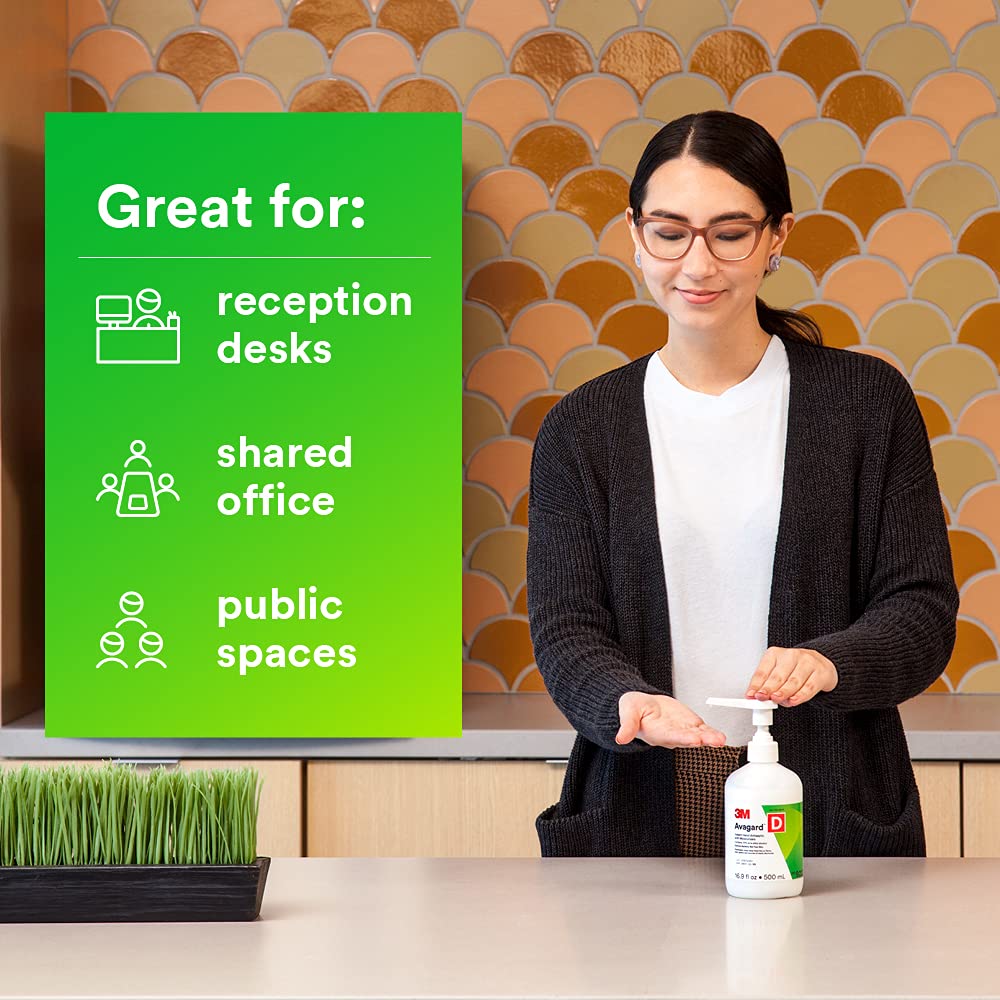 Hand antiseptic pump bottle on counter as woman dispenses sanitizer into her palm in a modern office setting