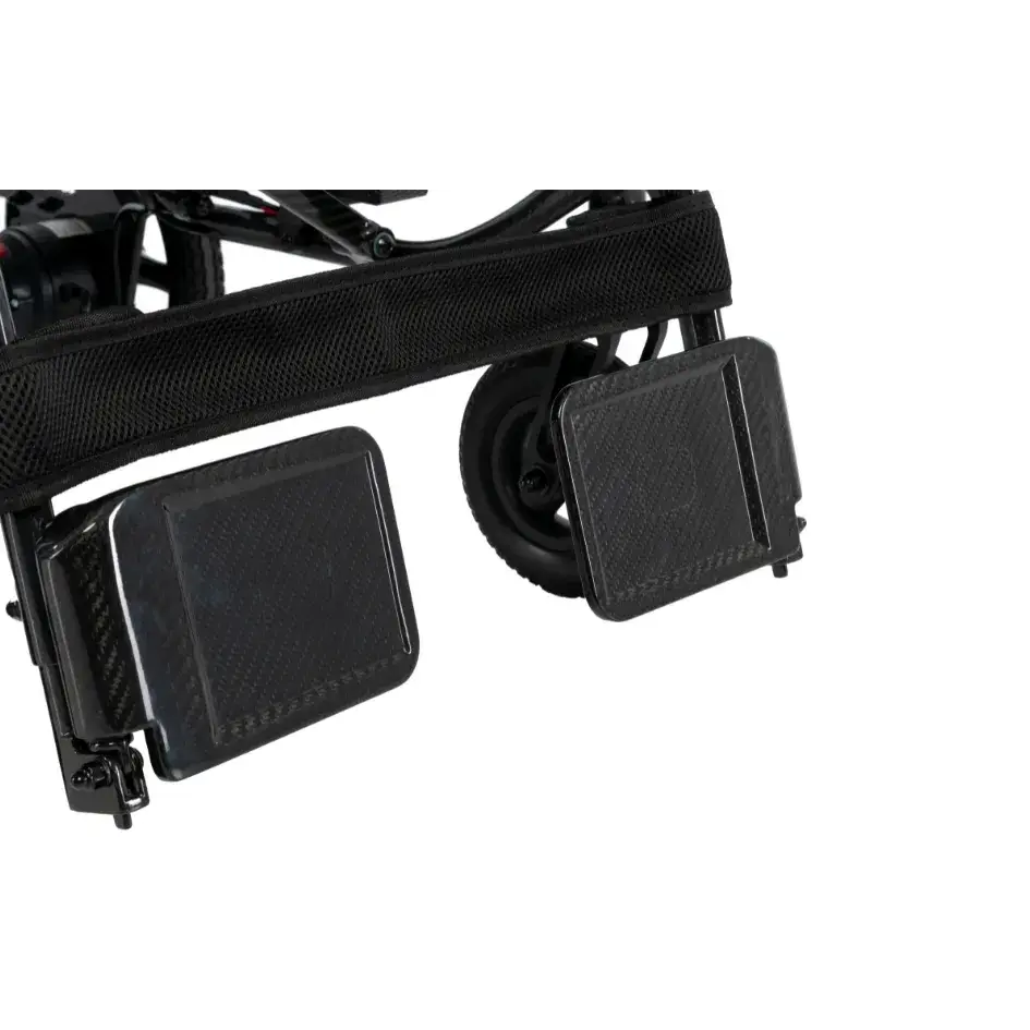 Power wheelchair footrests and front caster wheel detail on black carbon fiber frame with mesh seat sling visible above