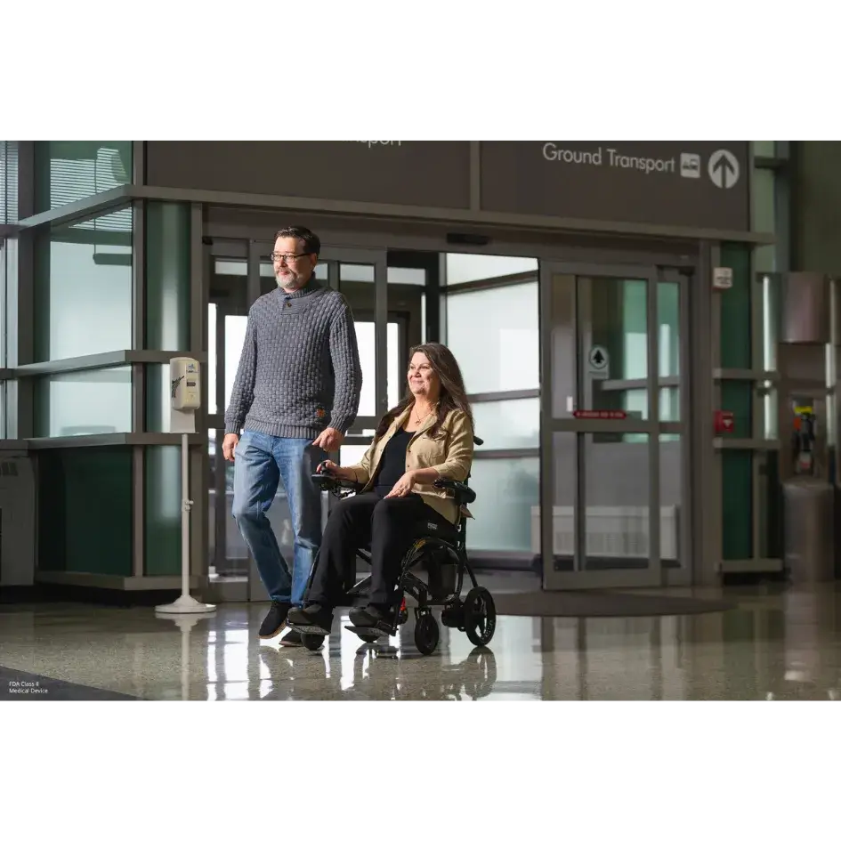 Power wheelchair being pushed by a companion through an airport terminal near a Ground Transport exit