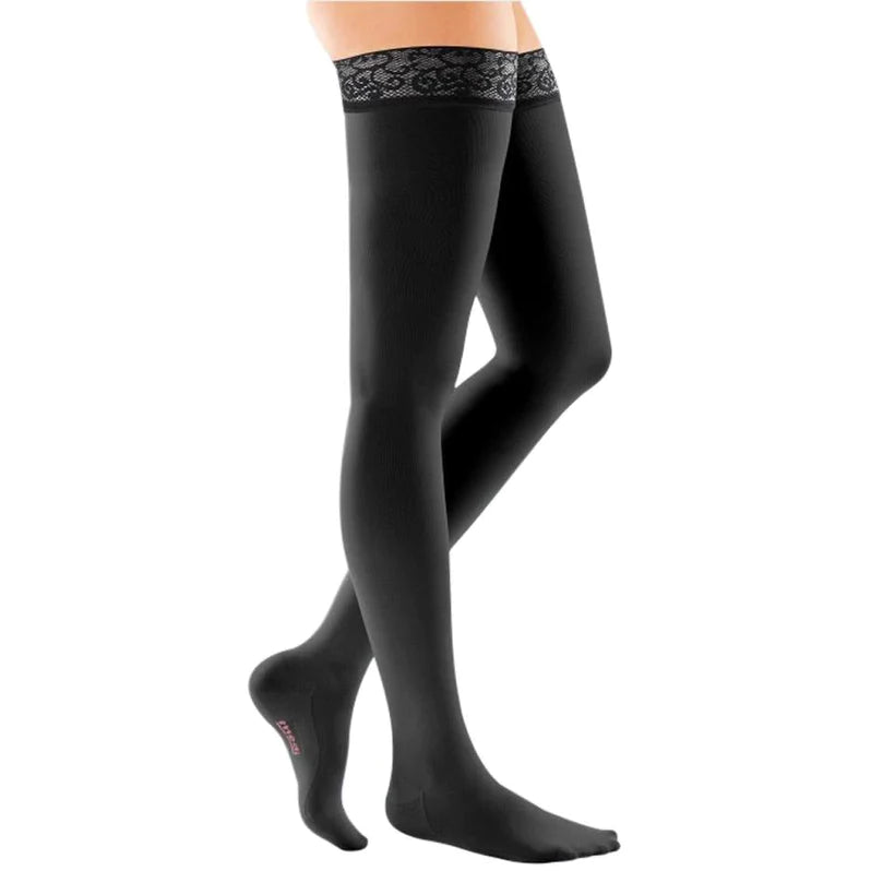 Compression thigh-high stockings in black with decorative lace silicone top band, shown on a woman's legs against white