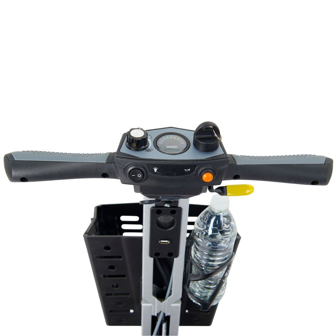 Power scooter tiller closeup showing handlebar controls, speed dial, battery gauge, USB port, front basket, and water bottle