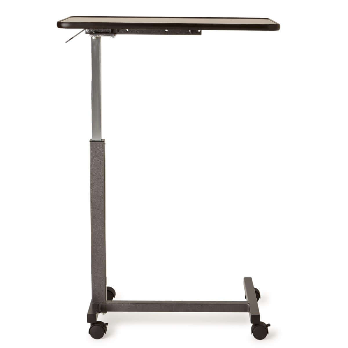 Overbed table with dark laminate top, silver adjustable post, dark metal H-base frame, and four swivel casters