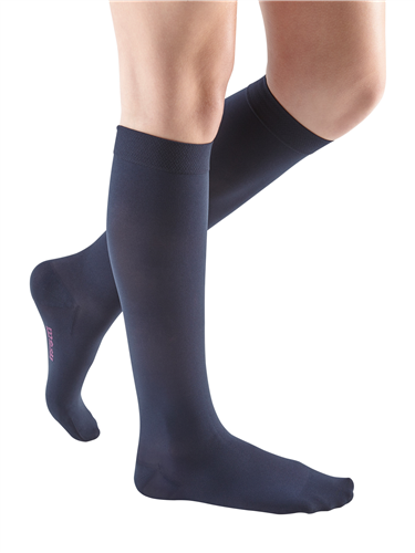 Compression knee-high socks in navy blue worn on a woman's legs, shown from mid-thigh down against a white background