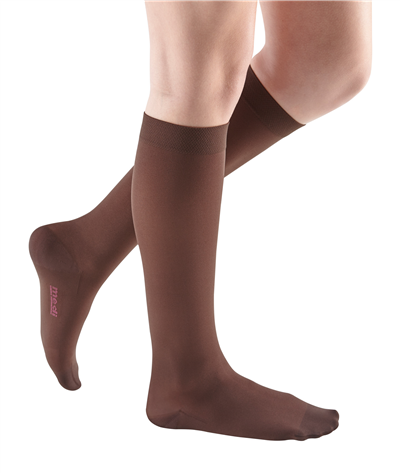 Compression knee-high stockings in brown worn on a woman's legs, shown from the knee down, closed toe style