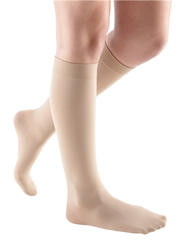 Compression socks in beige, knee-high closed toe style, worn on both legs against a white background