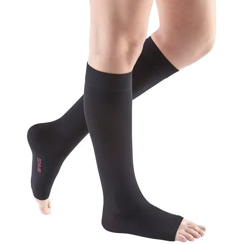 Compression stockings knee-high open-toe style in black, shown on a person's legs against a white background