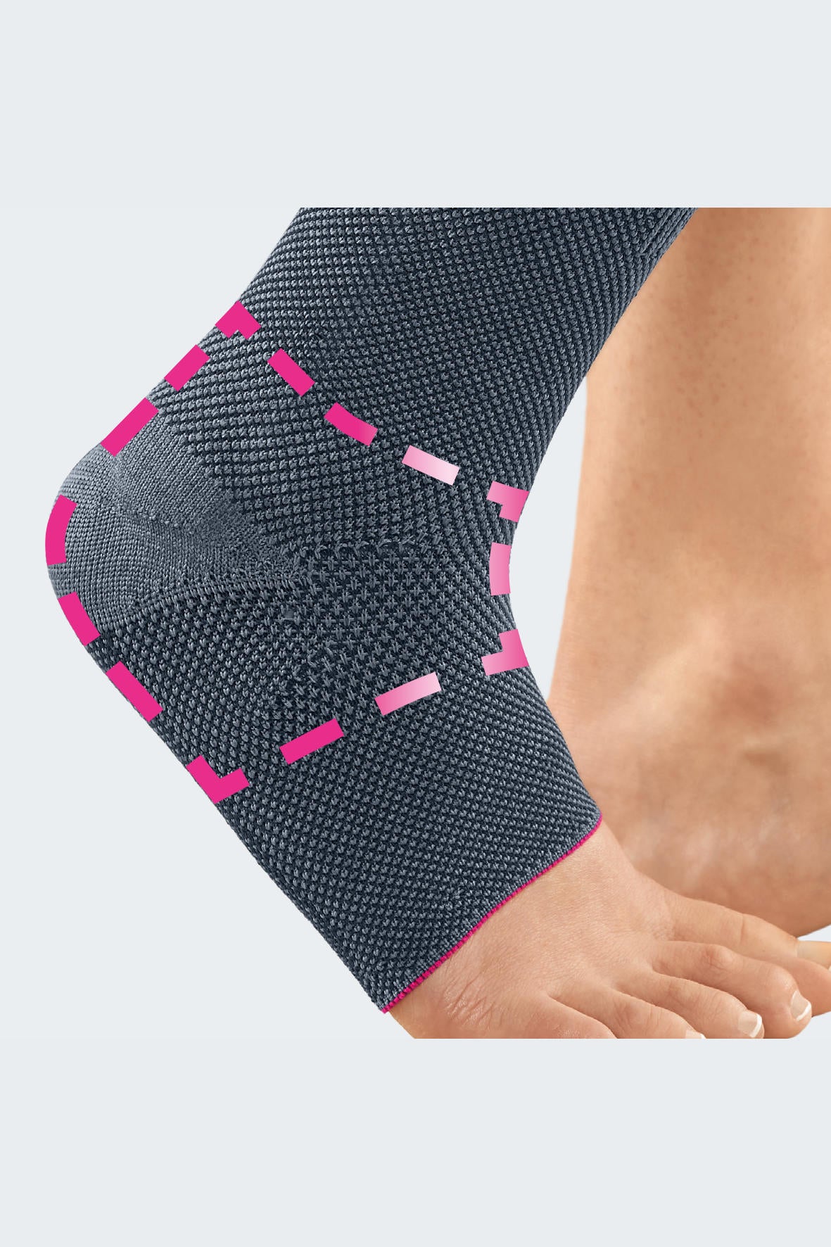 Ankle support in gray knit fabric with pink accent stitching worn on a person's ankle and lower leg, toes visible