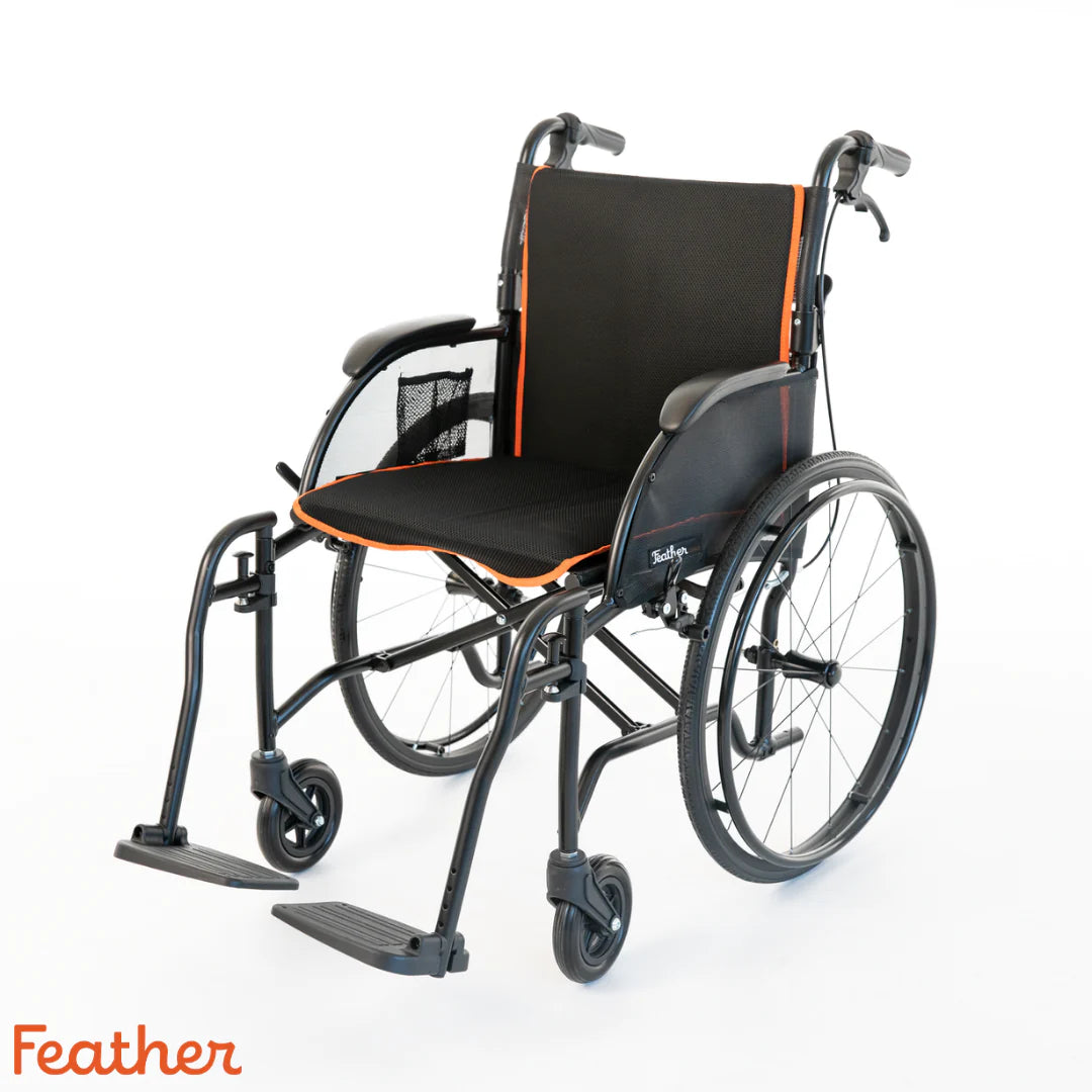 Lightweight wheelchair with black frame, mesh back, padded seat, orange trim accents, large rear wheels, and swing-away