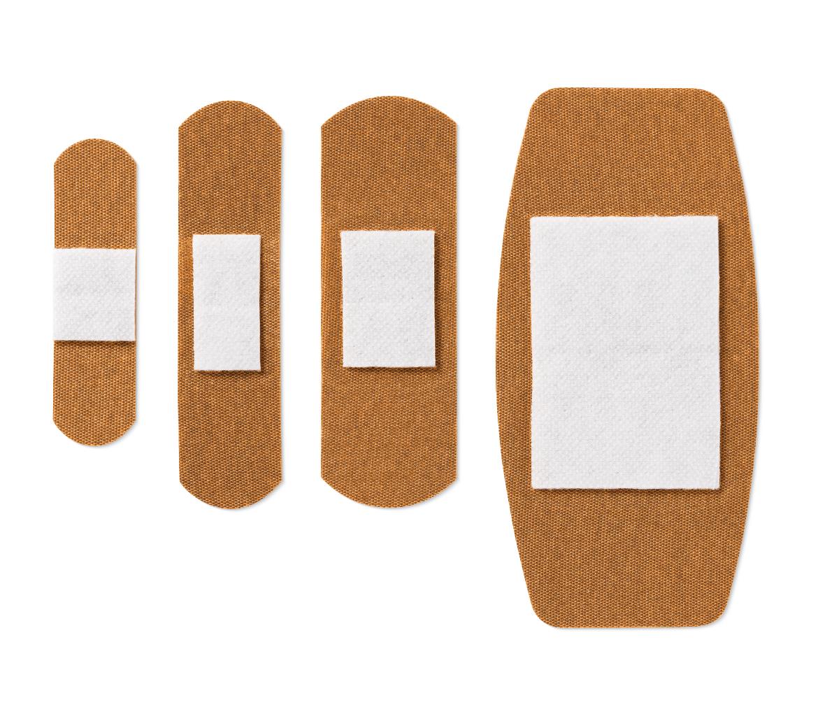 Adhesive bandages in four sizes with white absorbent pads on tan fabric backing, arranged smallest to largest on white