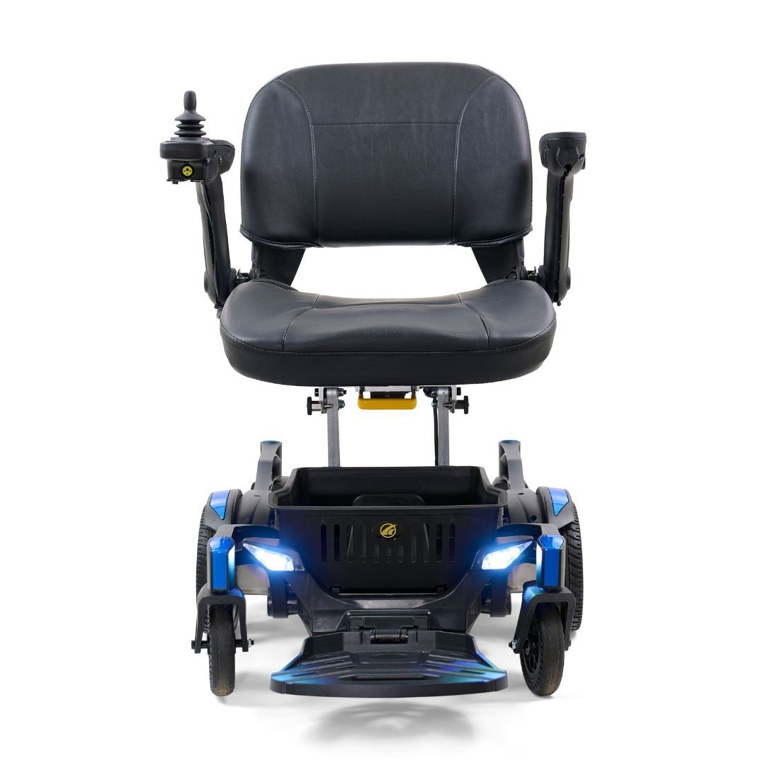 Power wheelchair with black padded seat, joystick controller, blue frame, front LED headlights, and four wheels, front view