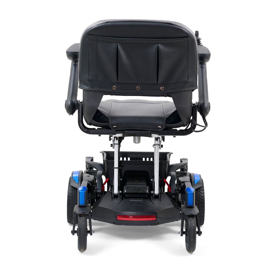 Power wheelchair rear view with black padded seat and back, blue accent panels, four wheels, and red rear reflector on white