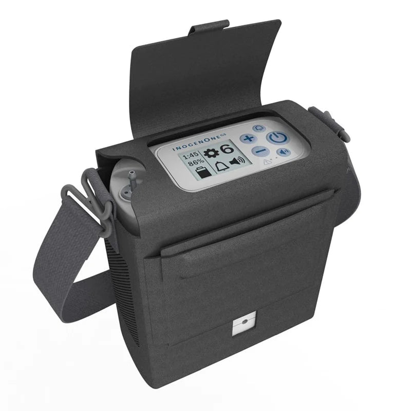 Portable oxygen concentrator in open gray carrying case with shoulder strap, showing control panel with display screen and