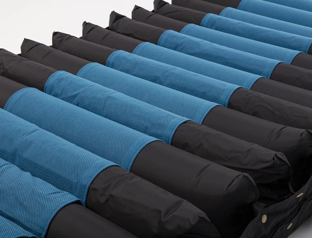 Alternating pressure mattress with alternating blue mesh and black nylon air cells, shown at an angle with zipper visible