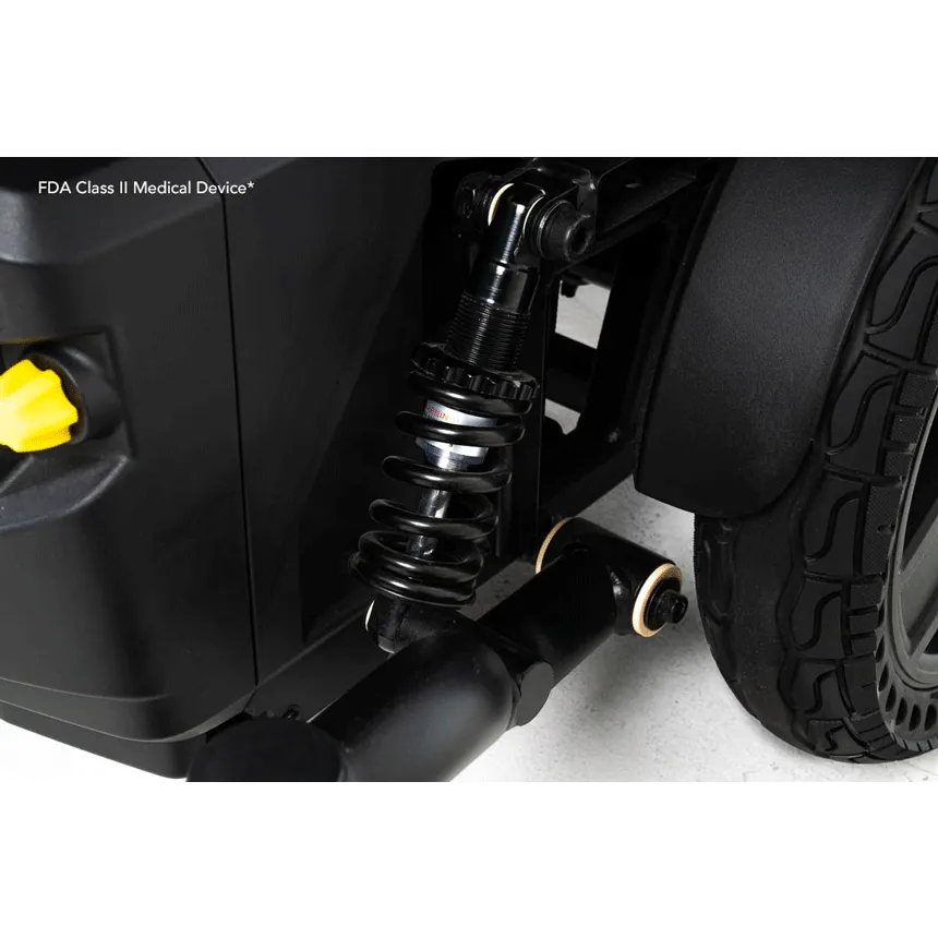Power wheelchair close-up showing black coil spring suspension system, frame, and rear wheel with textured tread