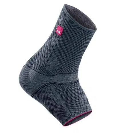 Ankle support brace in dark gray knit fabric with pink accent label and wraparound strap, shown on a foot form