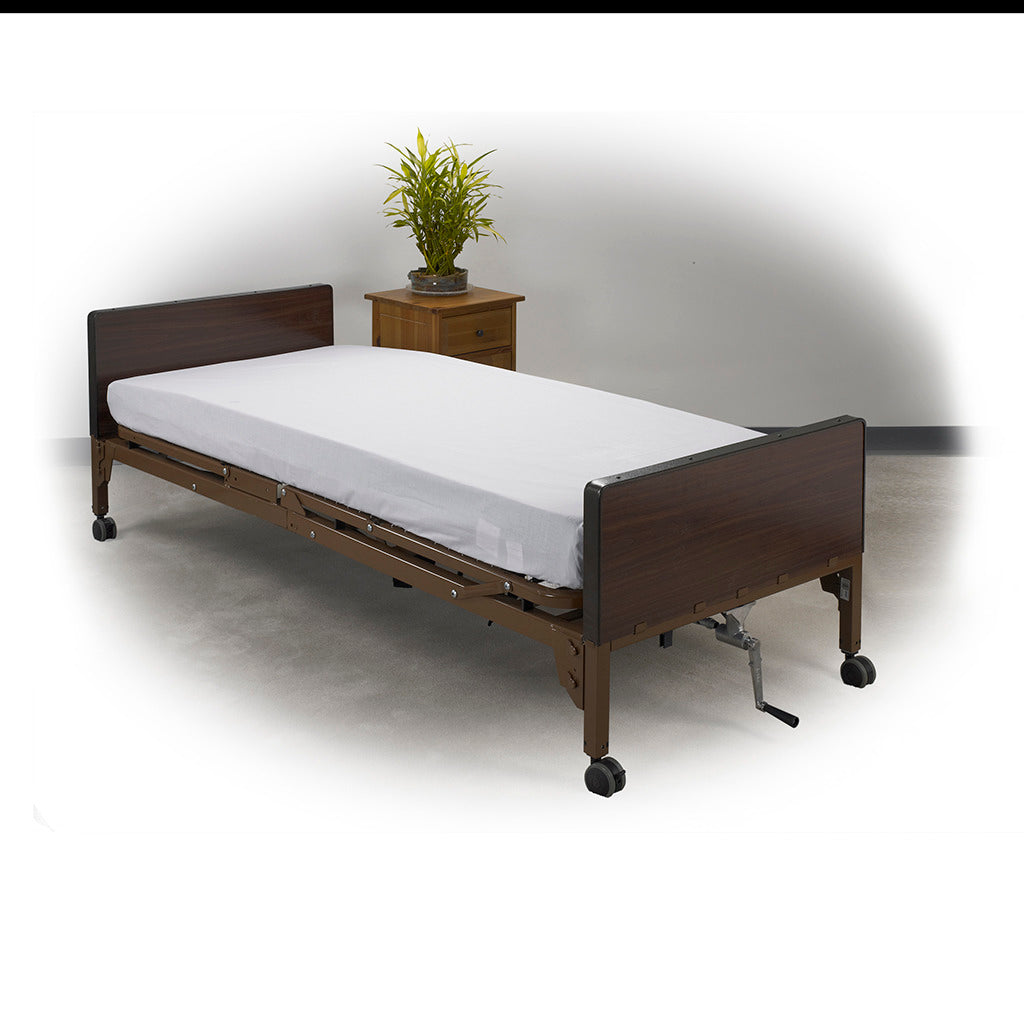 Hospital bed linen kit shown as a fitted white sheet on a home hospital bed with dark wood panels and casters