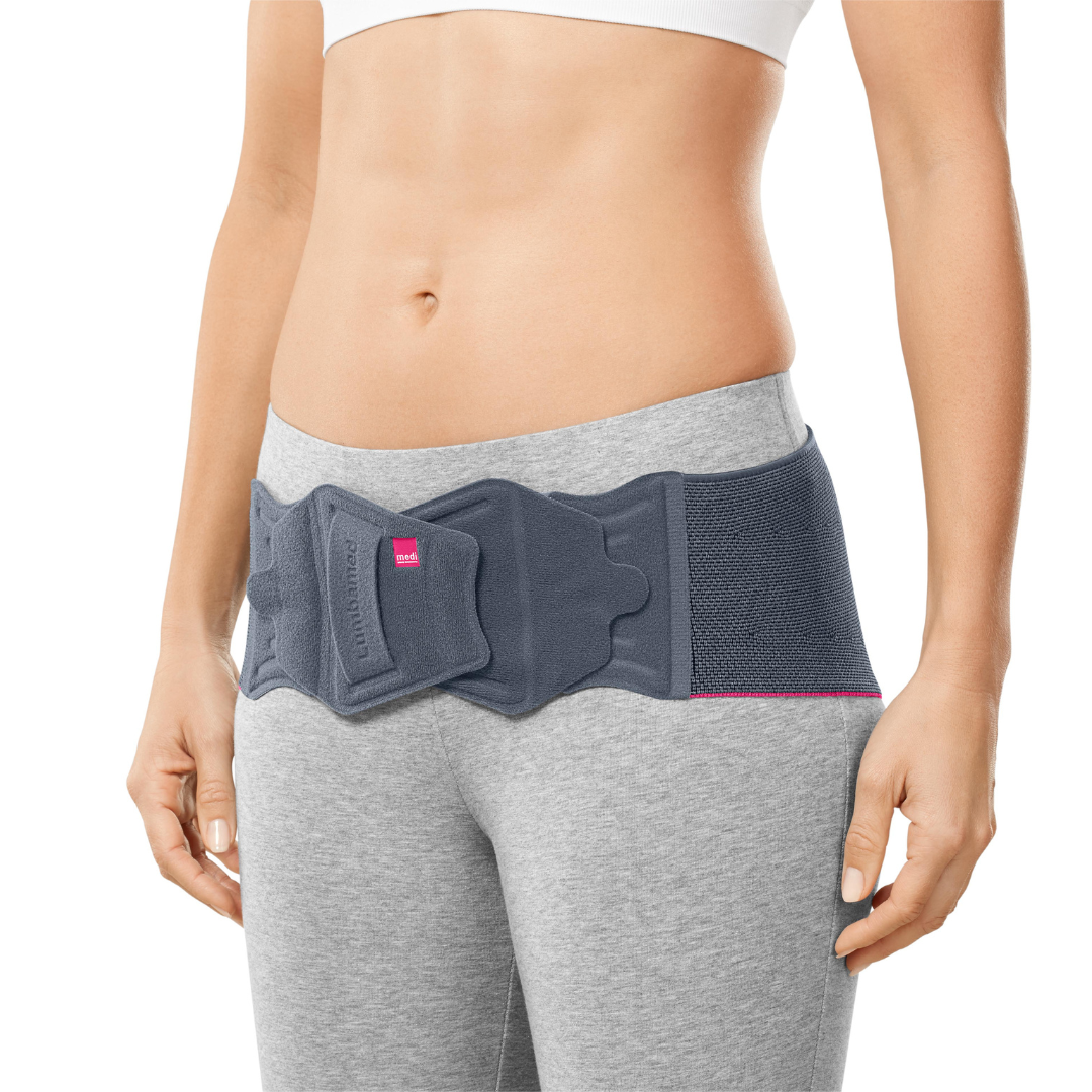 Lumbamed Sacro support belt in gray with pink trim worn around the lower back and hips of a female model