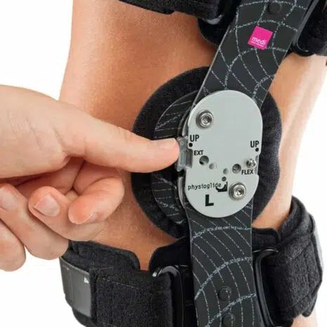 M.4s Comfort Knee Brace worn on leg with hand adjusting the hinged flex/extension dial on the side panel