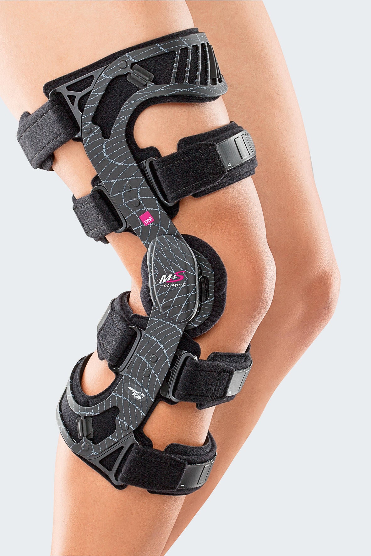 M.4s Comfort knee brace in gray and black with hinged frame, padded straps, and patella pad, worn on a bare leg