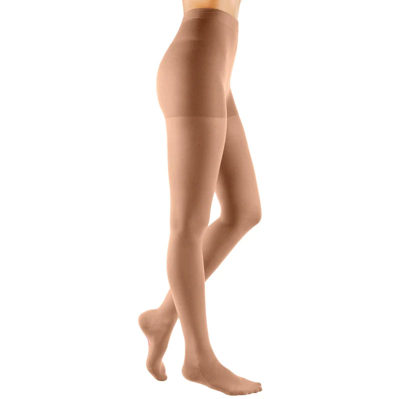 Compression pantyhose in beige worn on a woman's lower body, shown from the side against a white background