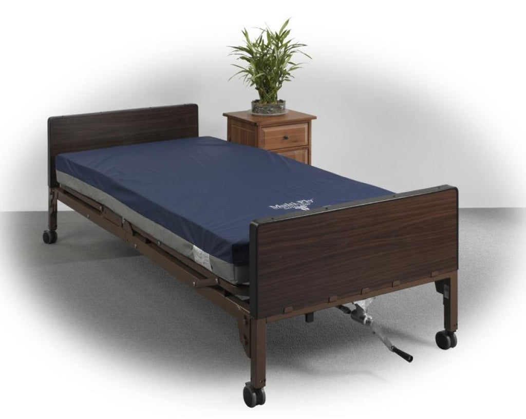 Foam hospital bed mattress with navy blue cover on a home hospital bed with dark wood panels and casters, nightstand with