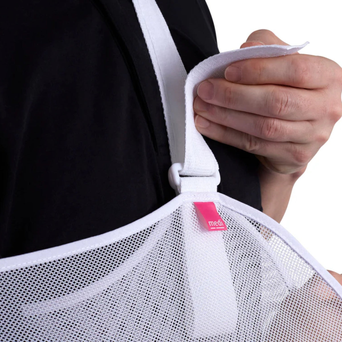 Protect arm sling with white mesh cradle and adjustable neck strap being fastened by a person wearing a black shirt