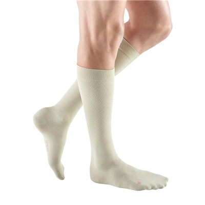 Compression socks in beige worn on a man's lower legs, knee-high length with textured knit fabric and closed toe
