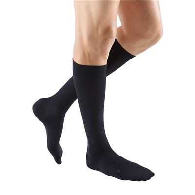 Compression socks in black knee-high length worn on a person's legs, shown from knees down against white background