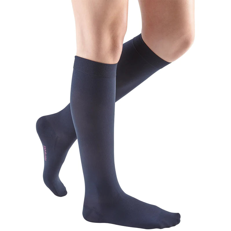 Compression socks in navy blue worn on a woman's lower legs, knee-high length with closed toe and smooth knit fabric