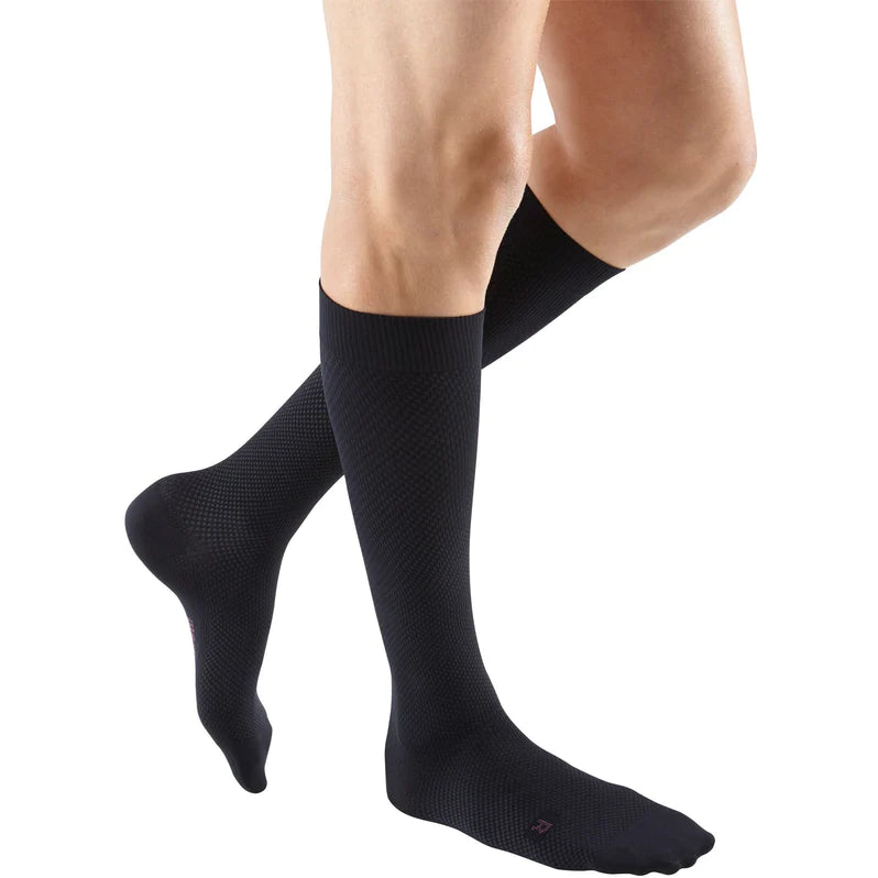 Compression socks in black with textured knit pattern worn on a person's lower legs, knee-high closed toe style
