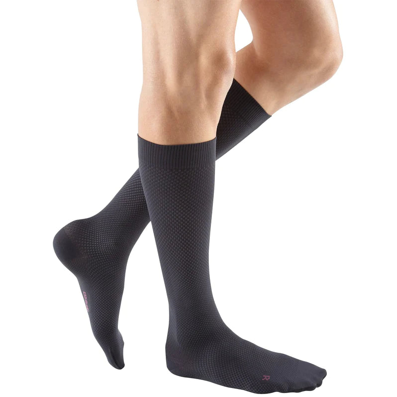 Compression socks knee-high in dark charcoal with textured pattern, shown on male legs against white background