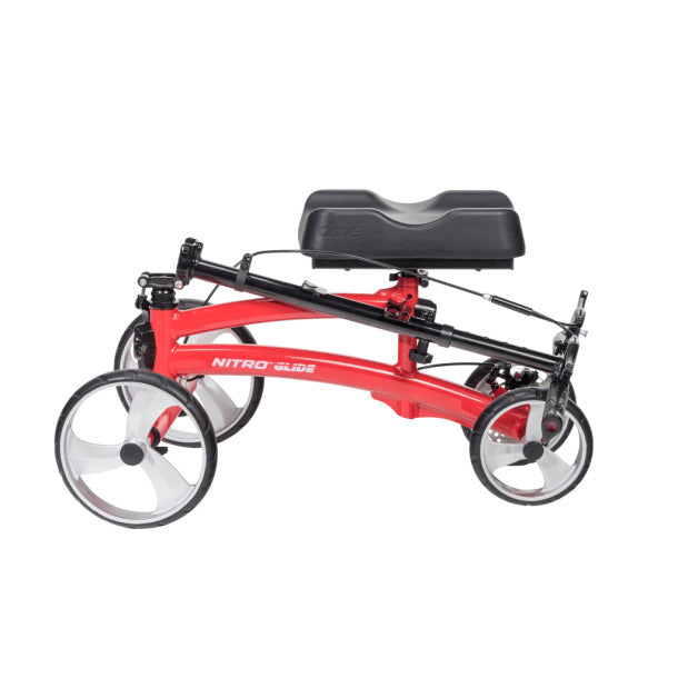 Knee walker with red frame, padded knee rest, four spoke wheels, and hand brakes, shown from the side on white background
